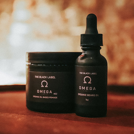 The Black Label Omega Organic Beard Oil 1oz dark glass dropper bottle beside Omega Organic Oil Based Pomade 4oz black jar