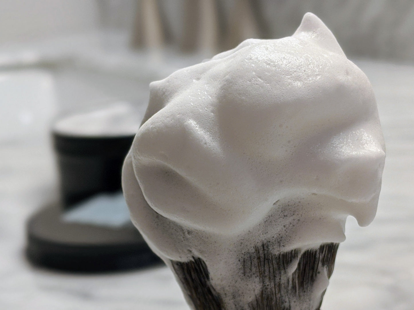 Foamy shaving cream on a brush with a blurred background
