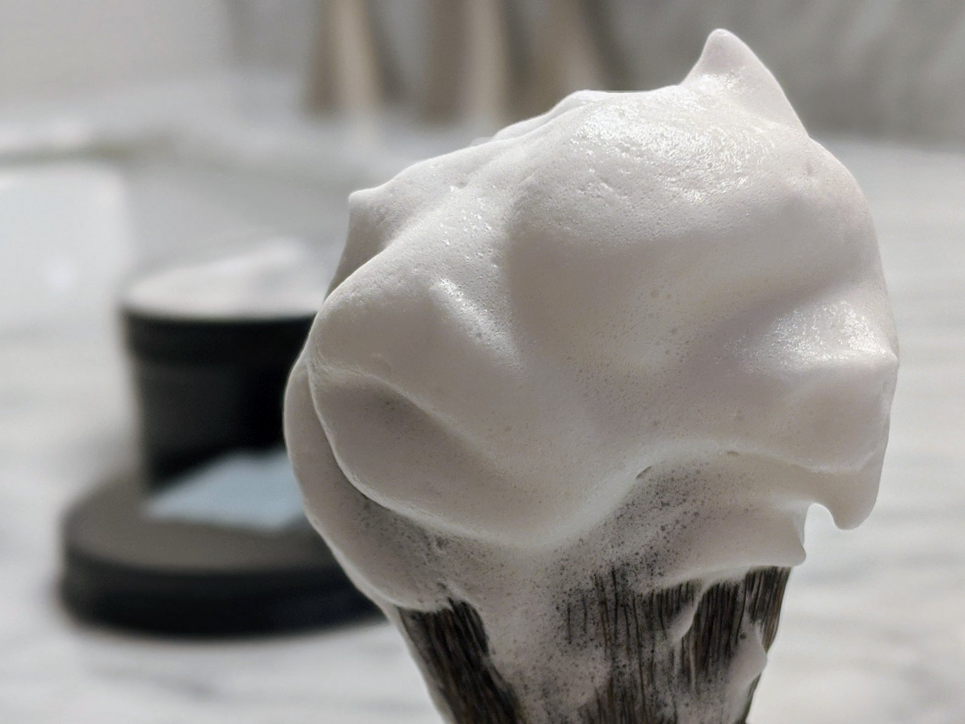 Foamy shaving cream on a brush with a blurred background