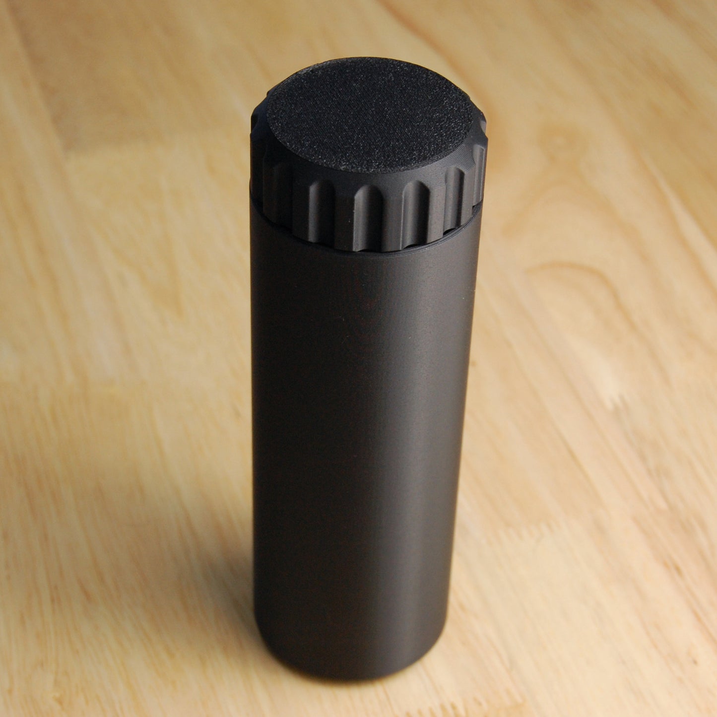 Black capsule brush case on a wooden background.