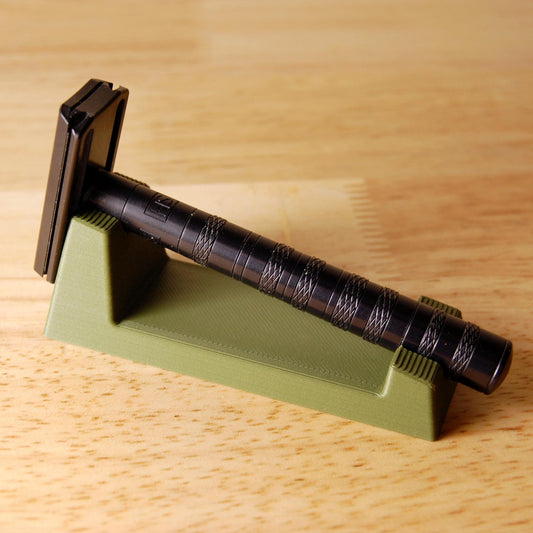 Stylish Henson Safety Razor Stand in Olive displaying a black Henson Razor, safety razor. The stand is on a wooden butcher block table.