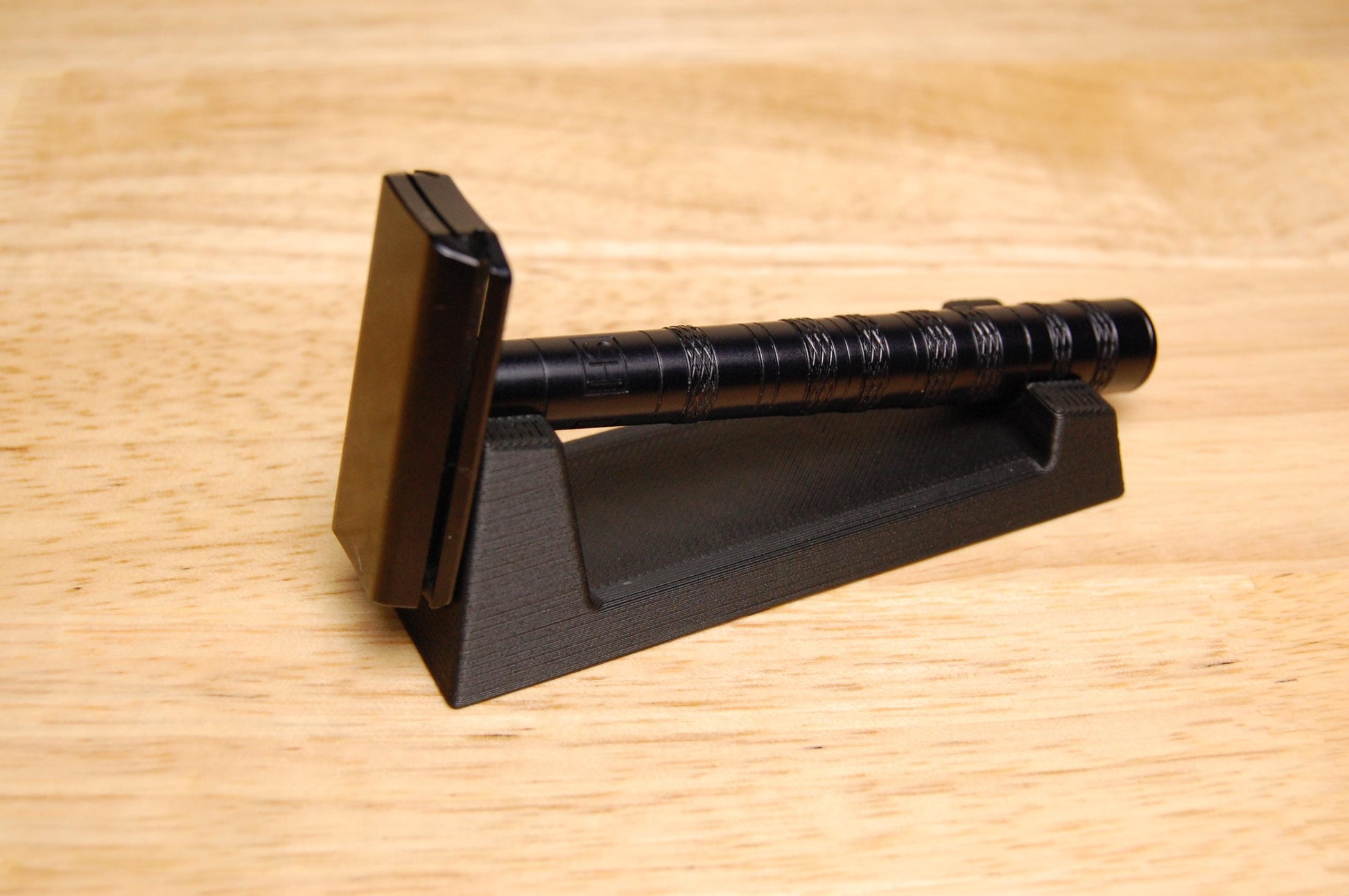 Stylish Henson Safety Razor Stand in black displaying a black Henson Razor, safety razor. The stand is on a wooden butcher block table.