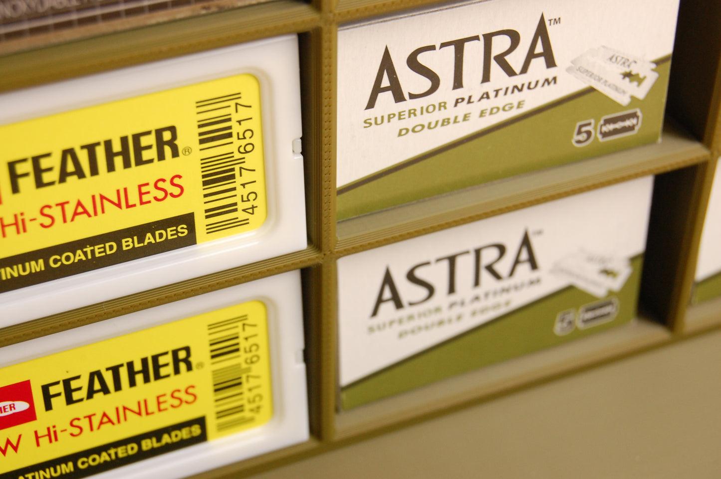 Close-up of Astra and Feather brand double edge razors on a shelf.