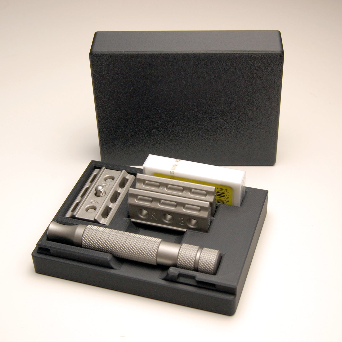 Sophisticated standard black Rockwell 6C/6S razor case on a white background. The razor and spare blades are in the case.