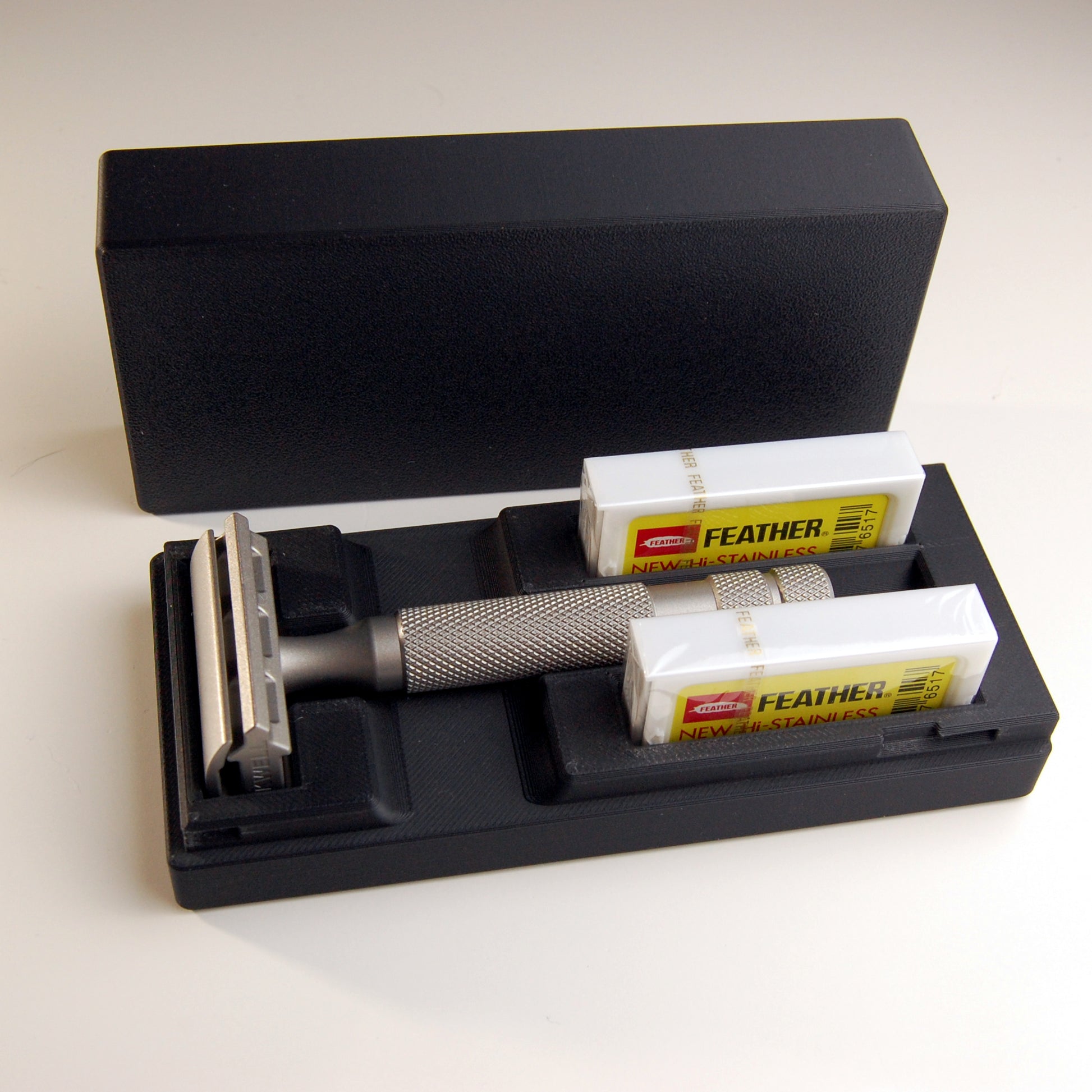 Black universal case with bare stainless steel Rockwell 6S.  Two feather blade boxes are stored alongside the razor.