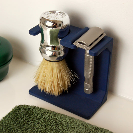 Shaving brush and razor on a blue stand with a green towel in the foreground.