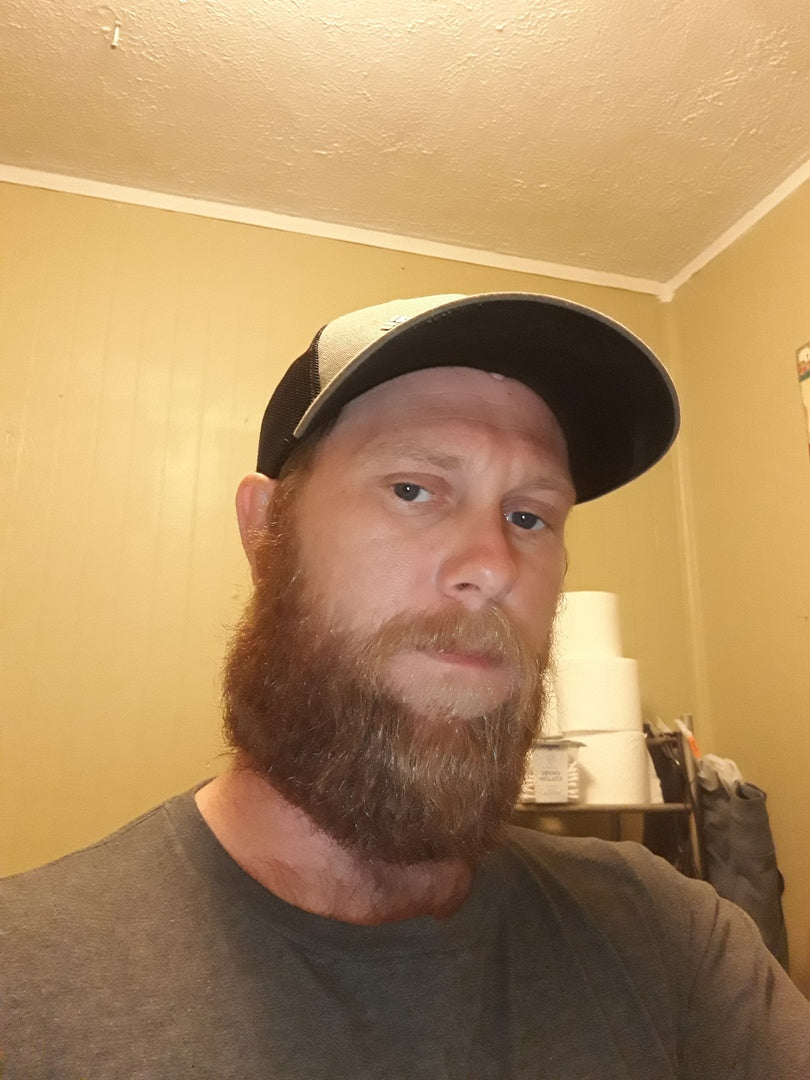 Man with full reddish-brown beard wearing a cap, showing beard grooming results from using organic beard oil