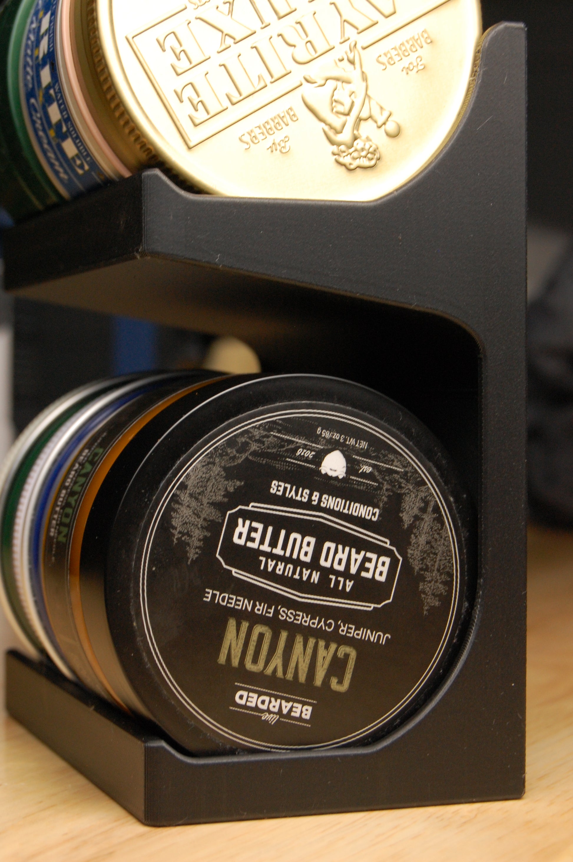 Stack of various beard balmsincluding a 'Canyon' brand product on a wooden surface.