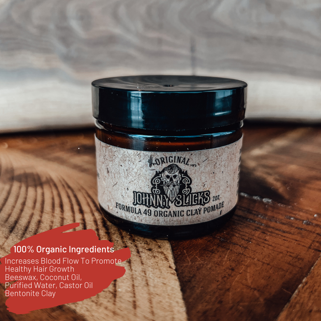 Johnny Slicks Formula 49 Organic Clay Pomade 2oz amber glass jar with black lid on wooden surface