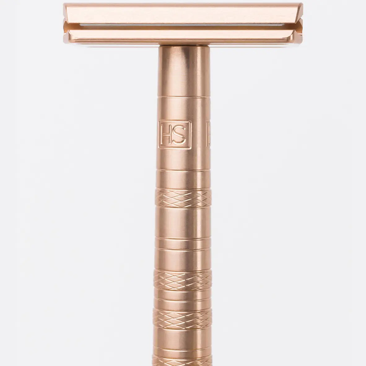 Rose gold Henson AL13 double-edge safety razor with knurled handle and engraved HS logo, close-up view