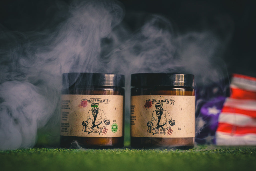 Two amber glass jars of Beast Balm After Action on grass, labeled 1000MG CBD and CBD Free, 4oz each, with American flag