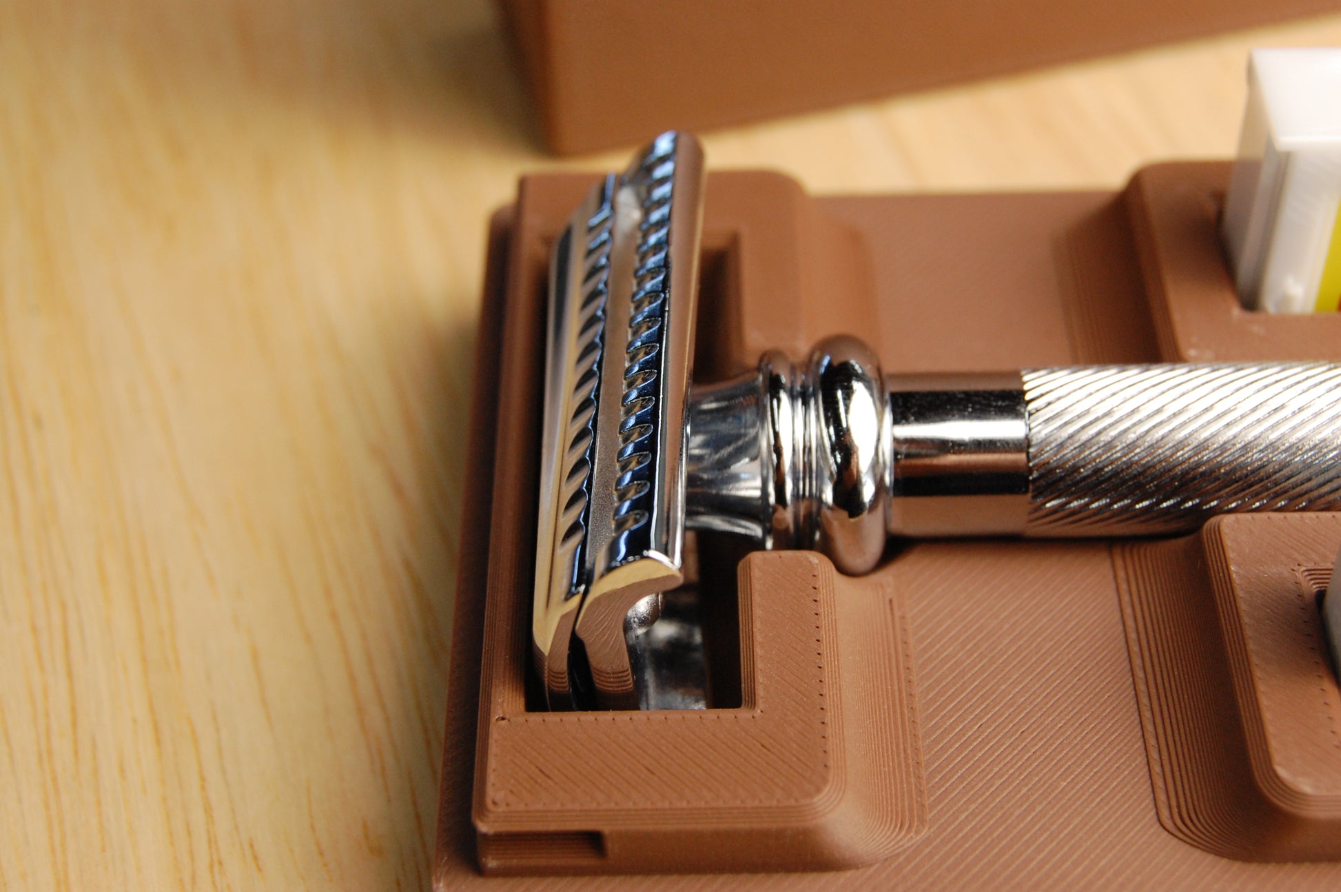Close-up of a Merkur 39C safety razor showcaseing the slant design with a brown case on a wooden surface