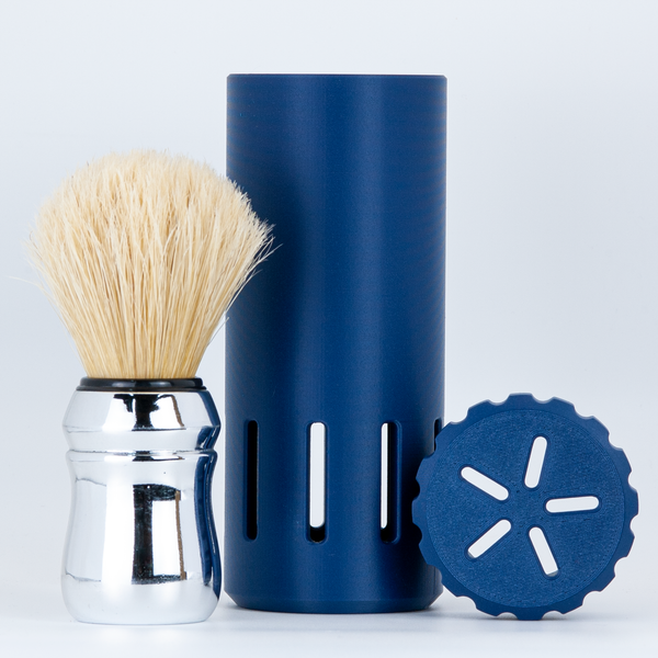 Shaving brush with chrome handle, navy blue capsule razor case and lid on white background