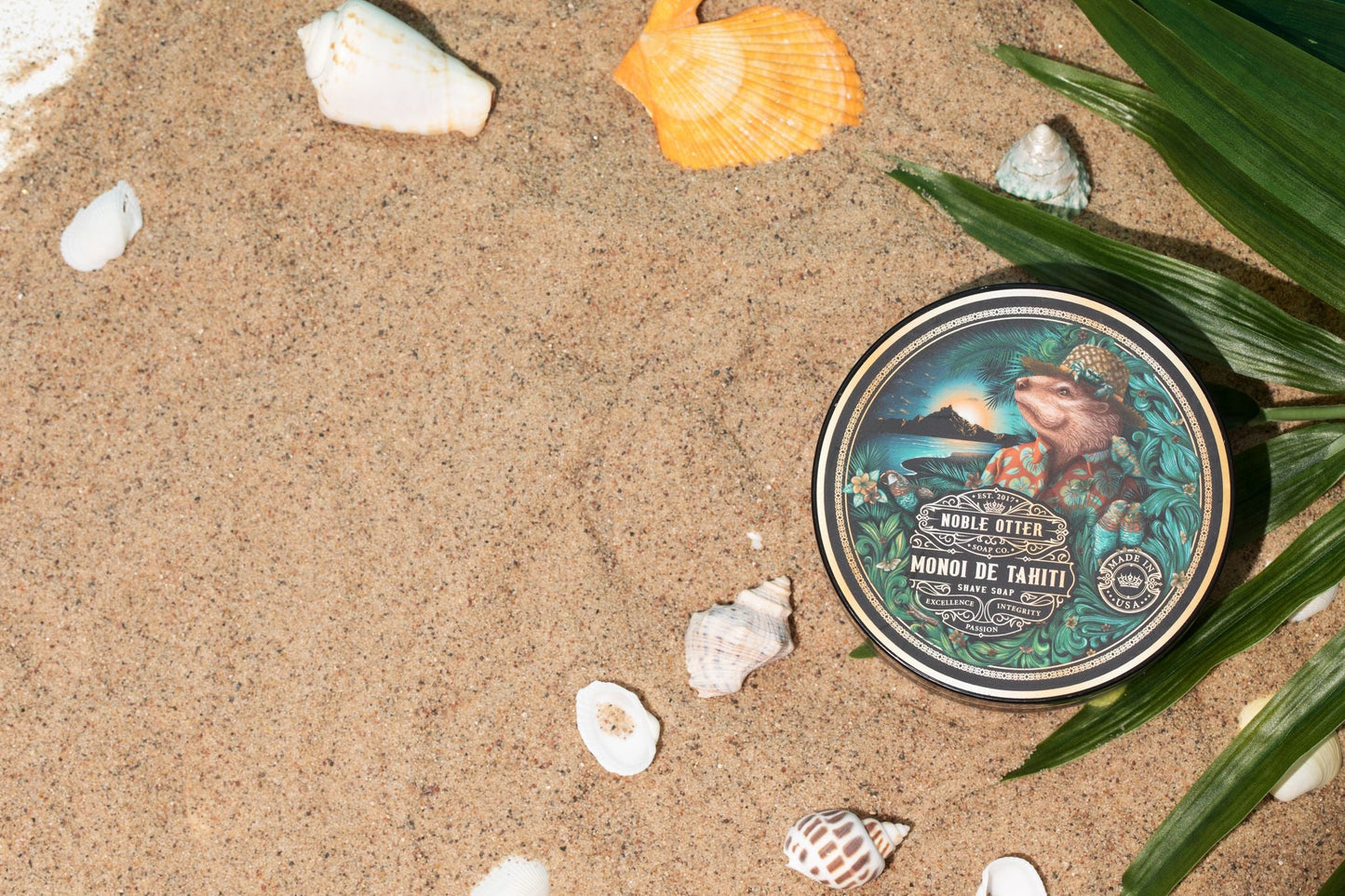Noble Otter have soap container with a tropical design on a sandy background with shells and leaves