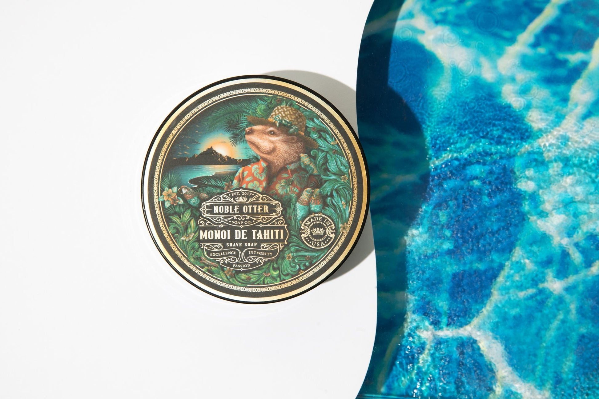 Noble Otter Tahiti shave soap on a white background with water on the right side.