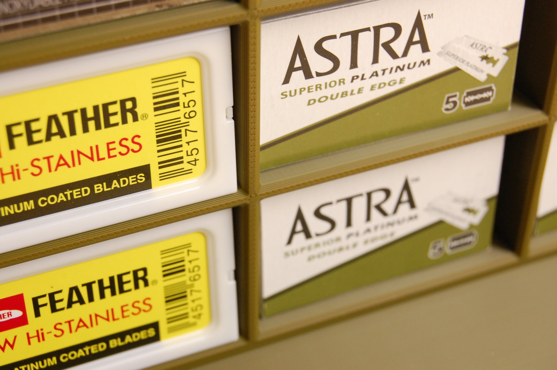 Close-up of Astra and Feather brand double edge razors on a shelf.