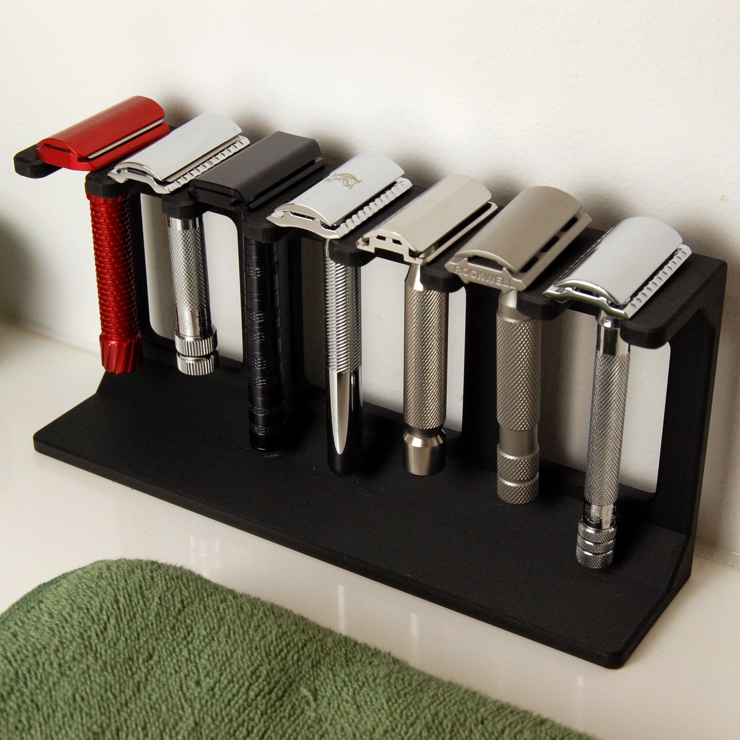 Seven razor display stand in black sitting on a white bathroom counter