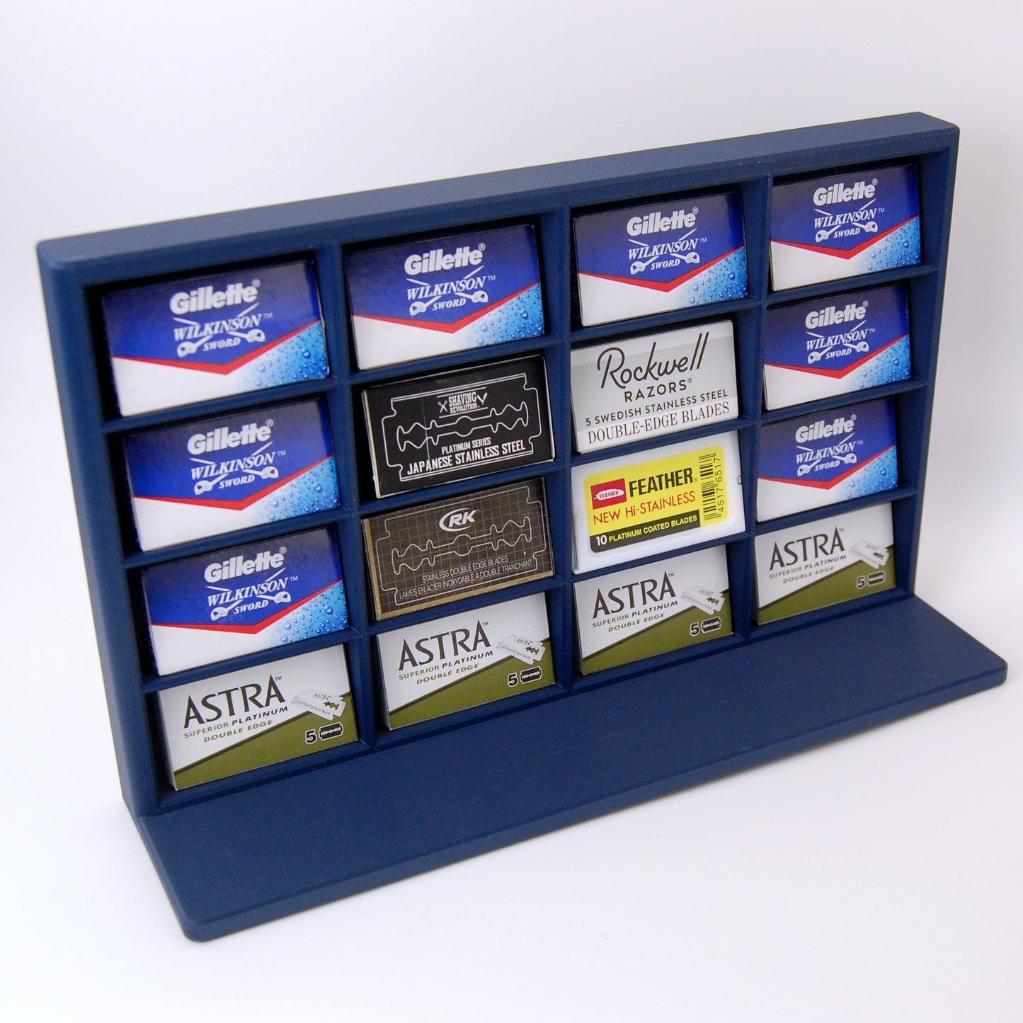 Various razor blade tucks stored in a navy blue razor blade display stand on a white background. Astra, Gillette, Shaving Revolution, RK, Rockwell and Feather blades are stored.