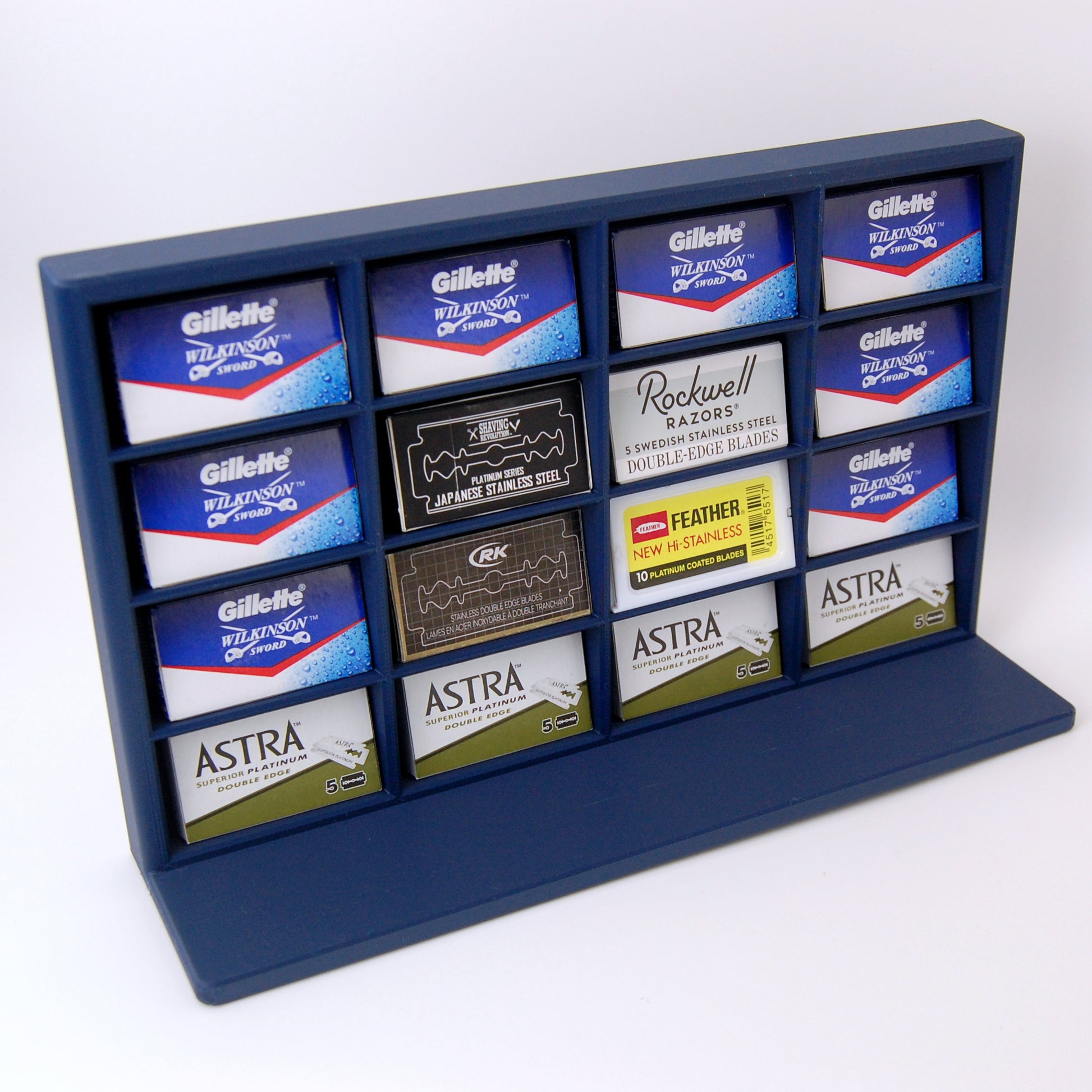 Various razor blade tucks stored in a navy blue razor blade display stand on a white background. Astra, Gillette, Shaving Revolution, RK, Rockwell and Feather blades are stored.