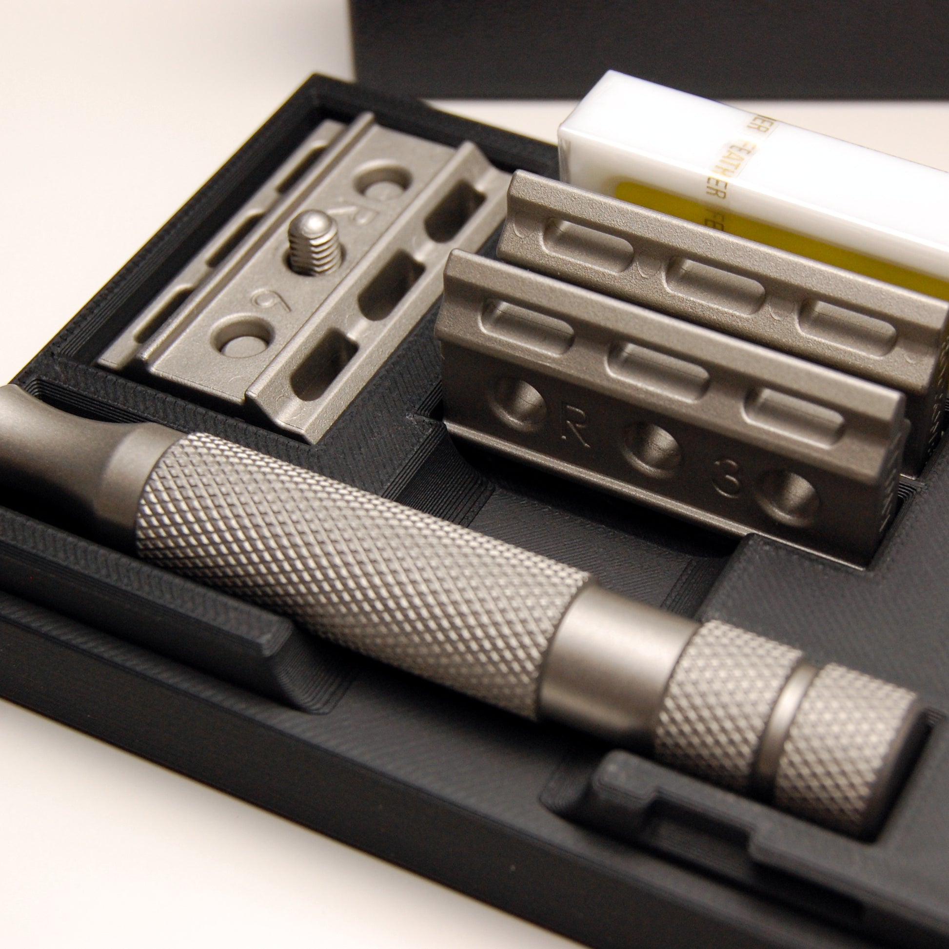 Close up of the Rockwell travel case shows the deep slot that fits the largest plate with a blade installed on the head.  The handle and other plates store neatly in their own spaces along with a 10-pack of feather razor blades.