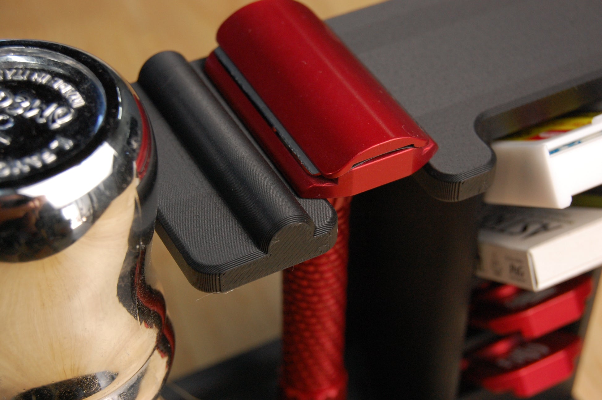 Close-up of a red Oliworks Razor on a black razor stand with a blurred background