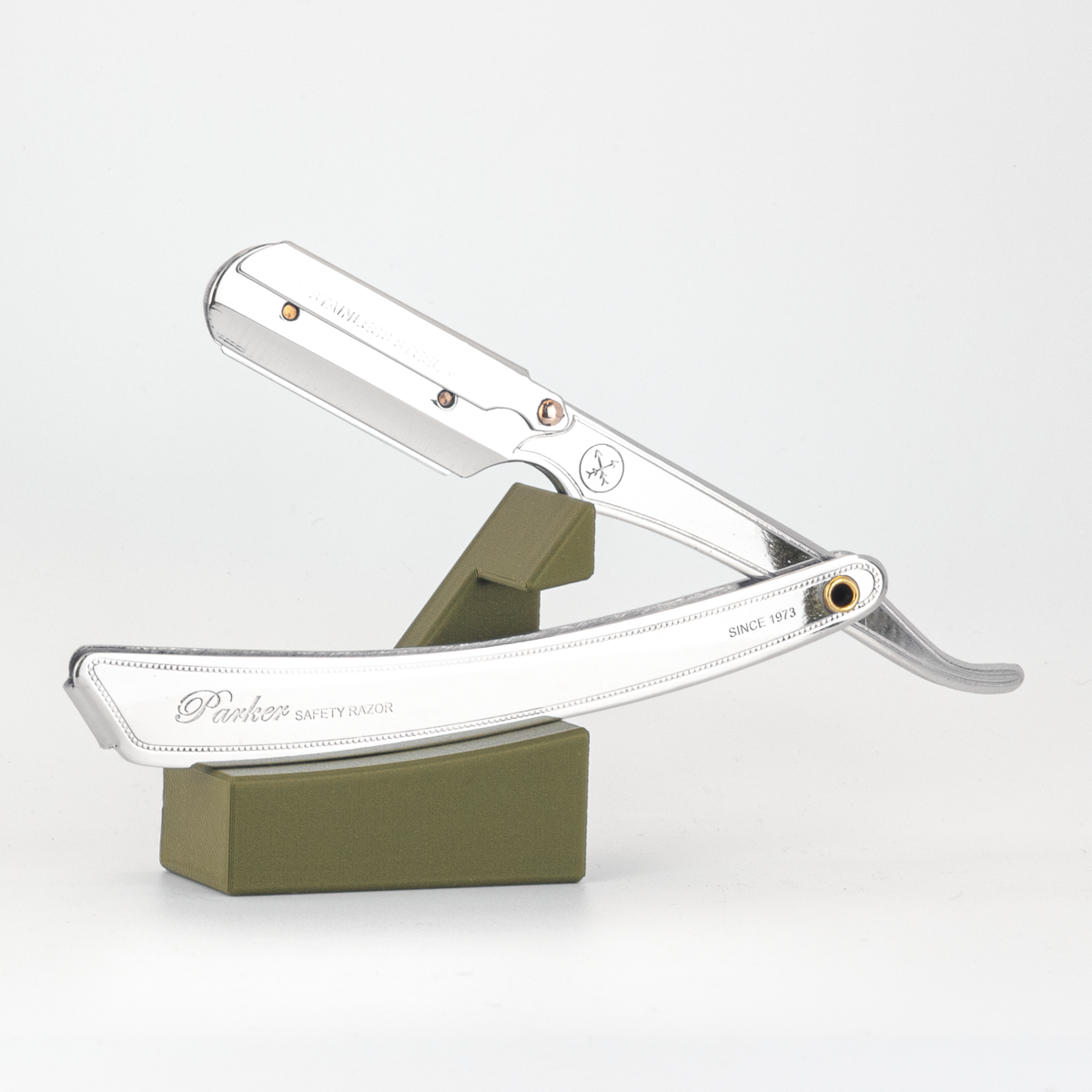Parker straight razor resting open on The Launch Pad army green stand, on a white background