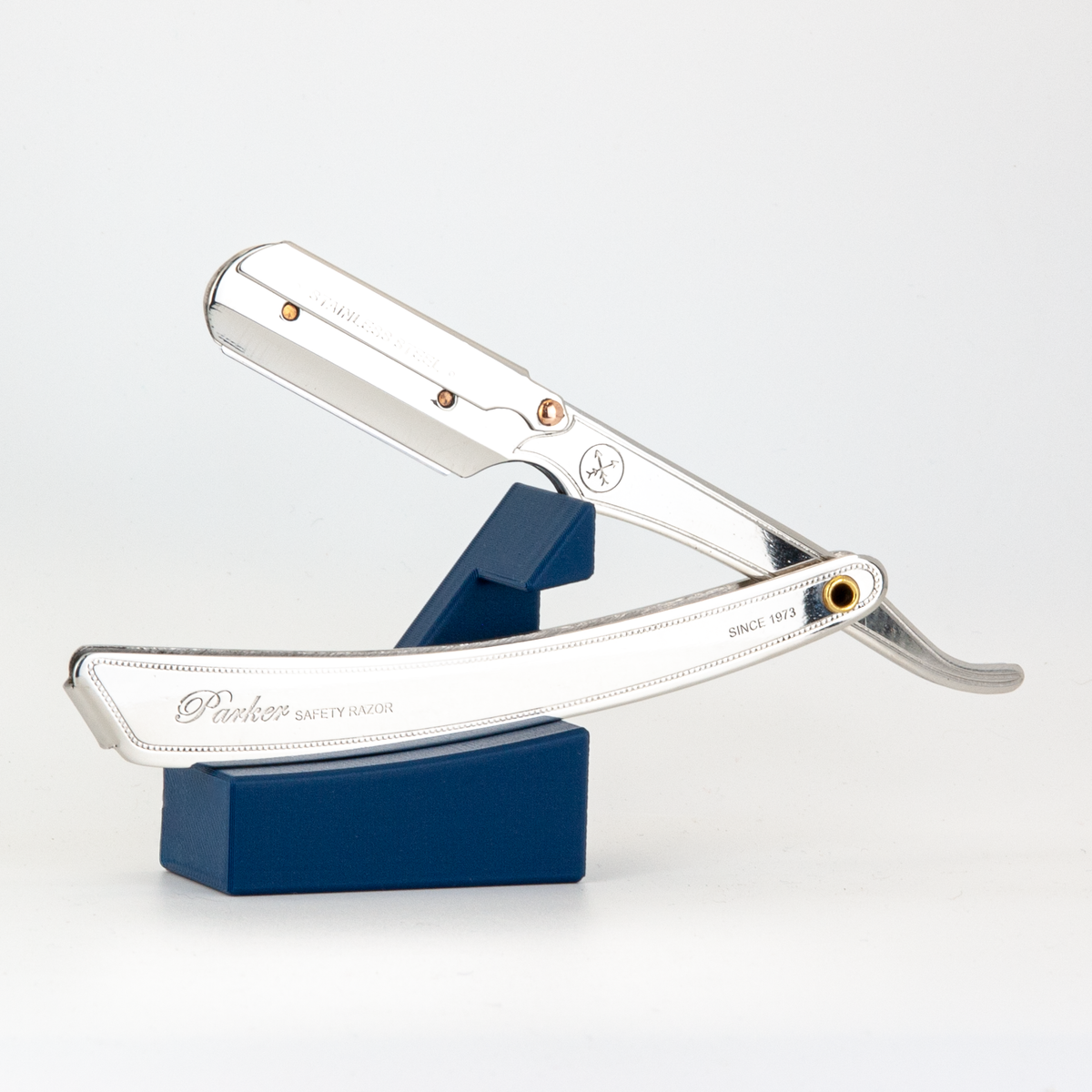 Parker straight razor resting open on The Launch Pad navy blue stand, on a white background