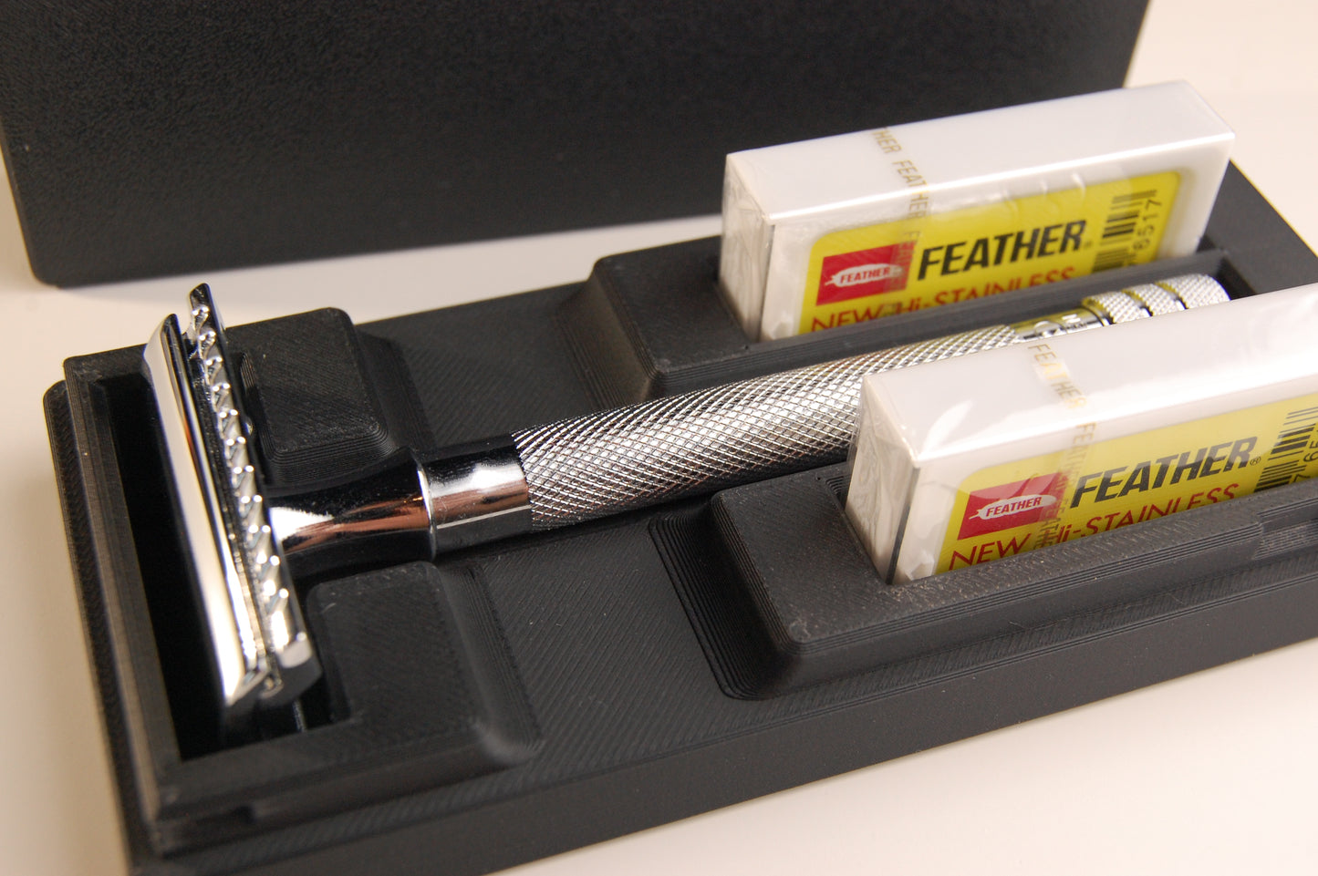 Black universal case with chrome Merkur 23C. Two feather blade boxes are stored alongside the razor.