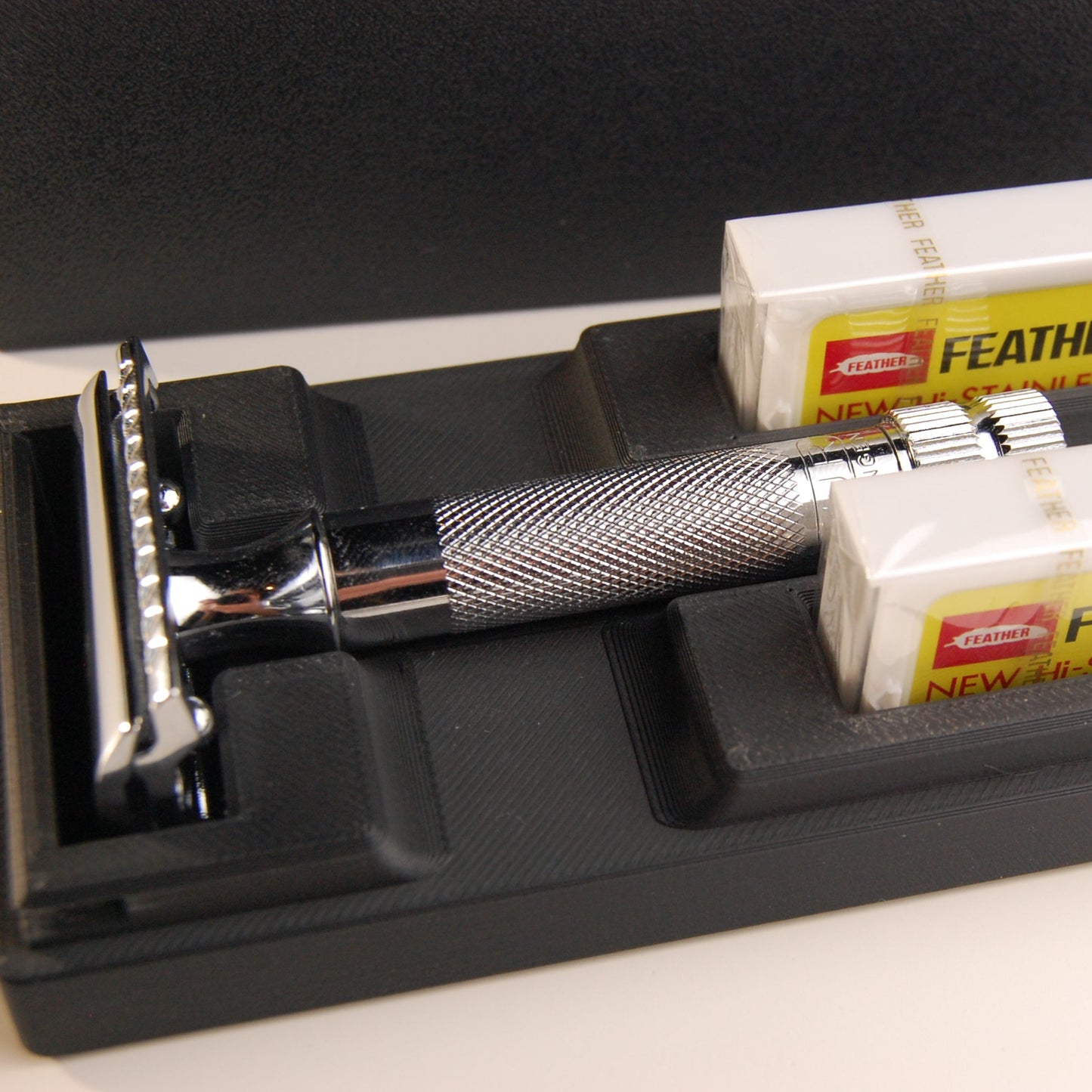 Black universal case with chrome Merkur 34C. Two feather blade boxes are stored alongside the razor.