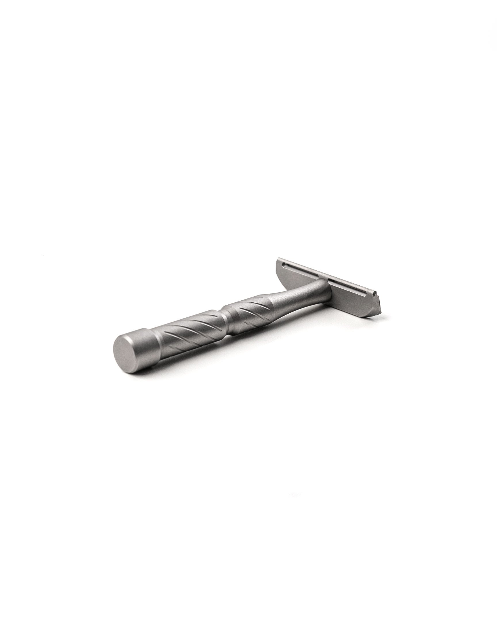 Silver titanium double-edge safety razor with diagonal-grooved handle, lying on white background