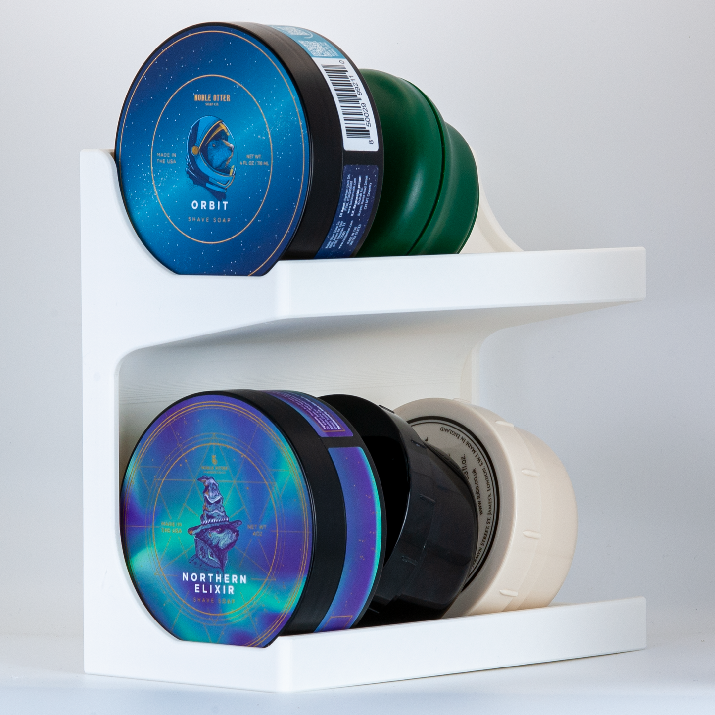 Collection of Noble Otter and other shave soaps on a white JRM shave soap stand on a white background.