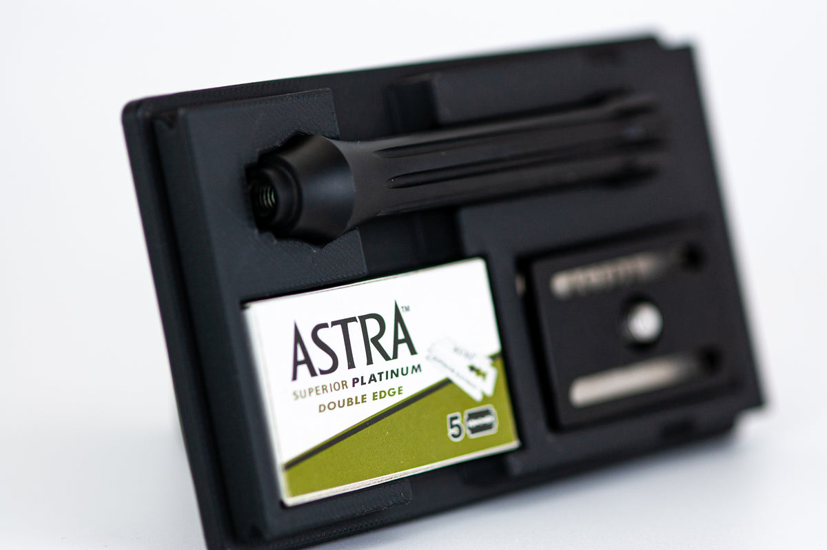 Angled close-up of the open Blackland Blackbird razor travel case showing the razor handle mount, Astra blade box, and blade dispenser
