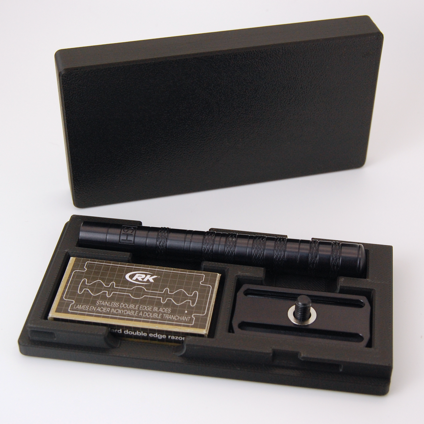 Henson case in black on a white background.  Black Henson razor is stored inside with a blade tuck of RKrazor blades.