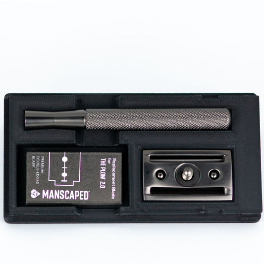 Open black Manscaped Plow 2.0 razor travel case with gunmetal razor handle, replacement blade box, and blade baseplate insert