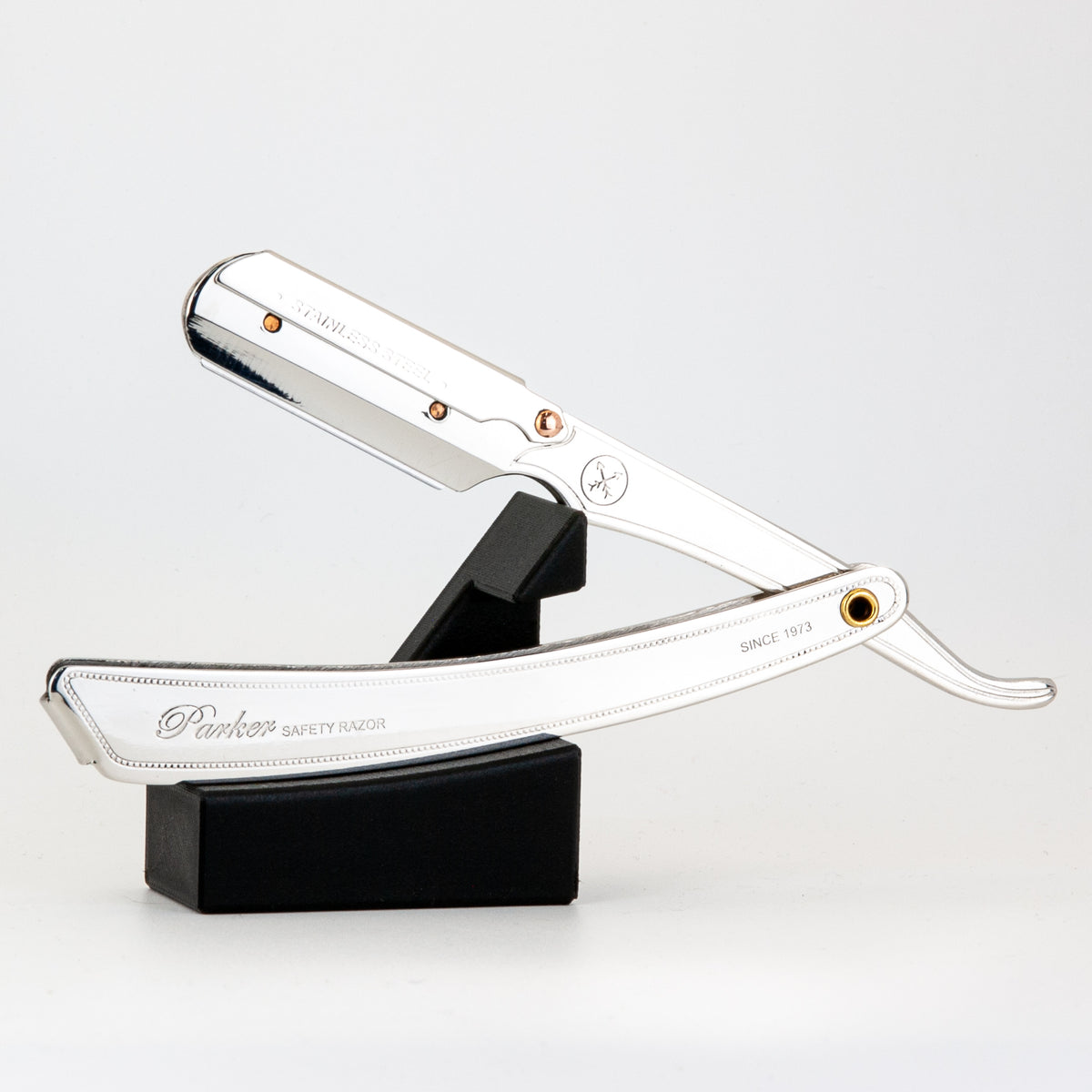 Parker straight razor resting open on The Launch Pad black stand, on a white background