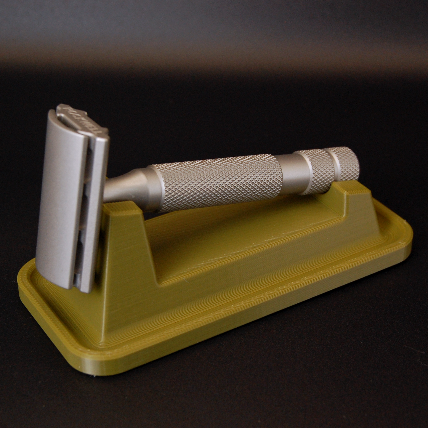 Universal razor stand with drip tray in army green on a black background.  Pictured with a Rockwell 6S razor.