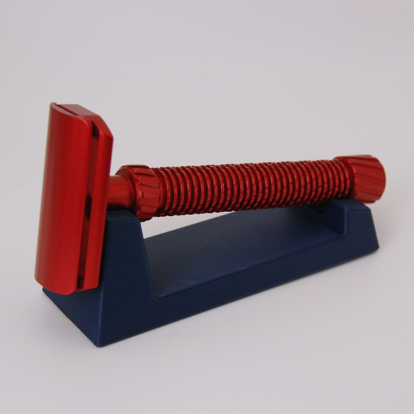 Universal razor stand in navy blue on a white background.  Pictured with a red Oliworks M3teorite razor.
