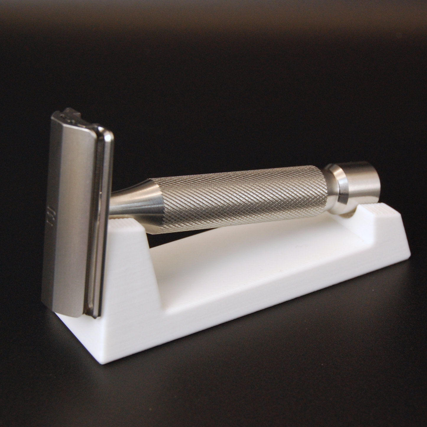 Universal razor stand with in white on a black background.  Pictured with a Maxwell June razor.